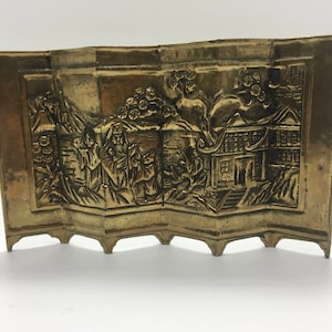 May include: A gold-colored metal decorative screen with an embossed design of a Chinese landscape scene. The screen is made of four panels that are connected together.