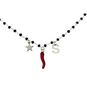 Gargantilla estilo rosario con cristales negros, colgantes de letras, estrella y cuerno de la suerte rojo. Hecho a mano.