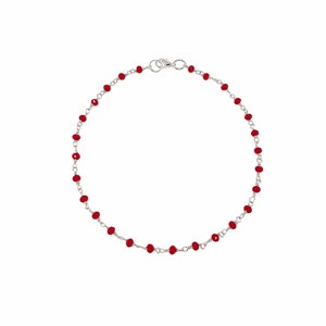 Puede incluir: Un brazalete de cadena de plata con pequeñas cuentas rojas.