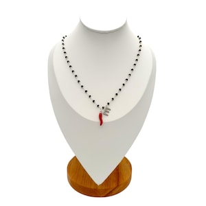 Gargantilha estilo rosário com cristais pretos e pingentes de letras e chifre da sorte vermelho. Feito à mão.