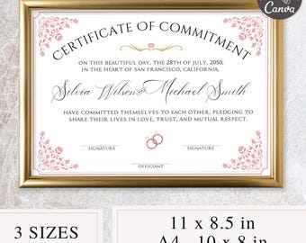 May include: A framed certificate of commitment with a gold border. The certificate has a pink floral design and the text "Certificate of Commitment". It includes the names Silvia Wilson and Michael Smith, and the date July 28, 2050. The certificate is available in 3 sizes: 27.9 x 21.6 cm, A4, and 25.4 x 20.3 cm.
