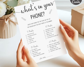 May include: A white game card with the text "what's in your PHONE?" in a handwritten style. The card lists items to check on a phone for points. The card is held by a person. The game is for a shower.