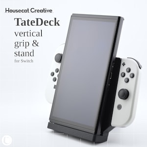 以下が含まれることがあります： 白いコントローラーが取り付けられた、黒いTateDeck垂直グリップとSwitch用スタンド。スタンドはSwitchを垂直に保持します。「Housecat Creative」と「TateDeck vertical grip & stand for Switch」の文字が見えます。