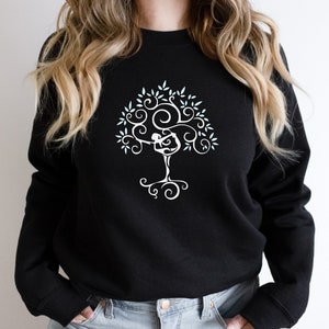 May include: Black sweatshirt with a white tree design. The tree features a person in a yoga pose within the branches. The design includes leaves and swirling patterns, creating a unique and artistic look. A comfortable and stylish top.