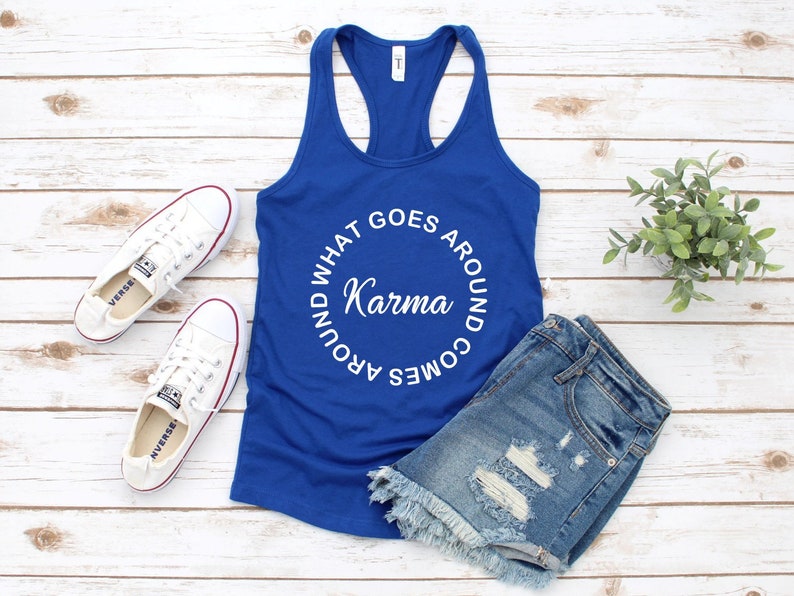 May include: A royal blue racerback tank top with the words "WHAT GOES AROUND COMES AROUND Karma" in a white circular design. The tank top is paired with denim shorts and white sneakers.