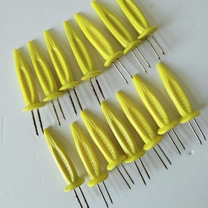 May include: A set of fourteen yellow corn-on-the-cob holders, each featuring a textured handle shaped like a miniature ear of corn and two sharp metal prongs extending from the base for securing food items during preparation or consumption.