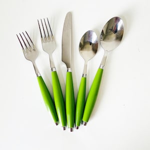 May include: A set of five stainless steel utensils: two forks, a knife, and two spoons. Each piece has a bright green handle with a silver band at the base. The utensils are arranged on a white surface.