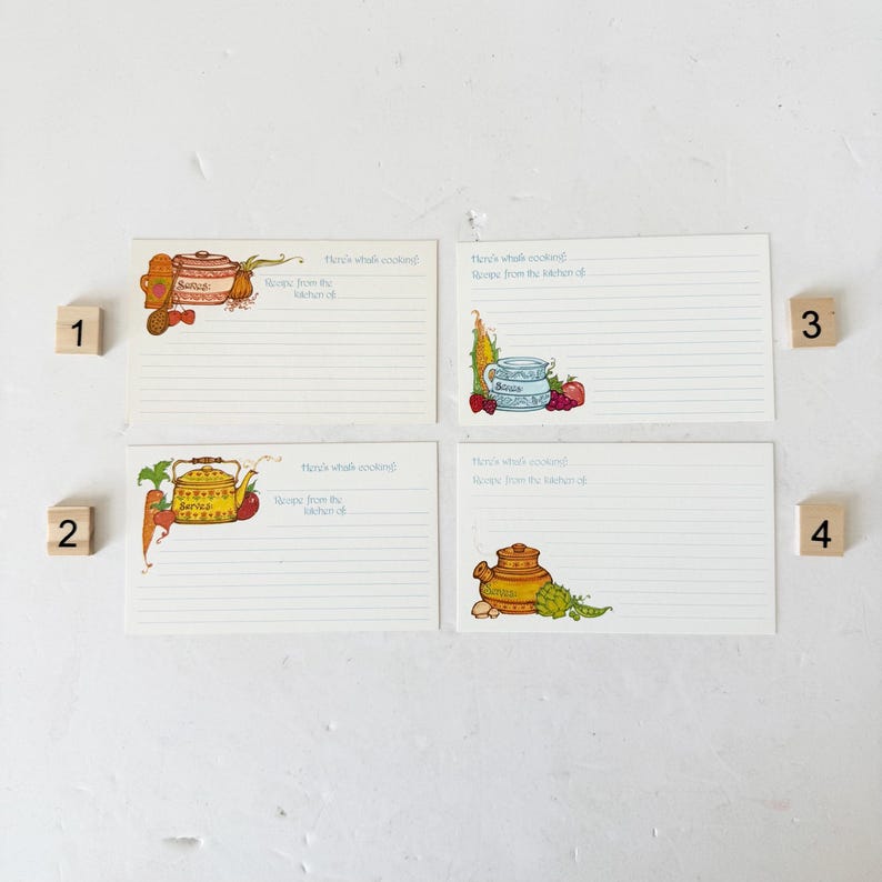 May include: Four vintage recipe cards with illustrated designs. Each card features a different image of kitchenware and produce, including a teapot, corn, and fruit. The cards have lined spaces for writing recipes.