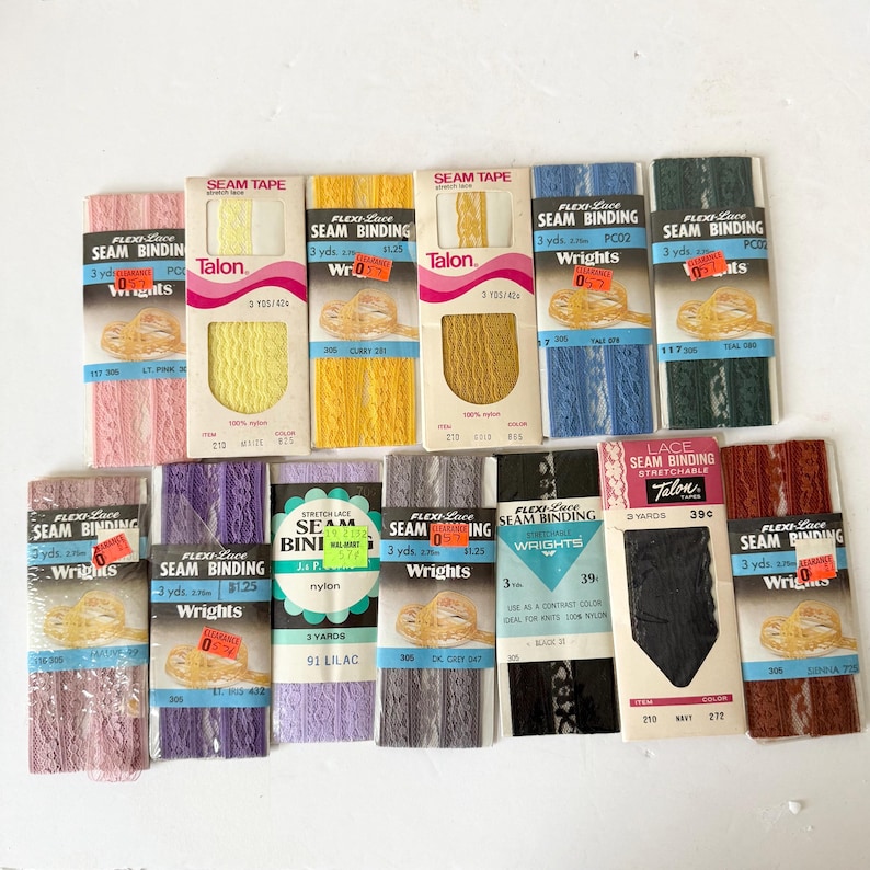 May include: A collection of vintage Flexi-Lace seam binding in various colors, including pink, yellow, gold, blue, and black. Each package contains 3 yards of binding and features the Wrights and Talon brands. Ideal for sewing and craft projects.