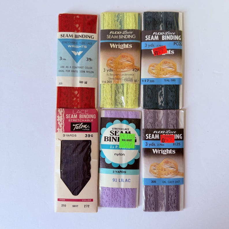 May include: A collection of vintage seam binding tapes in various colors, including red, yellow, black, purple, and gray. The packages feature the brands Wrights, Talon, and Seam Bini, with text indicating the length of each tape is 3 yards.