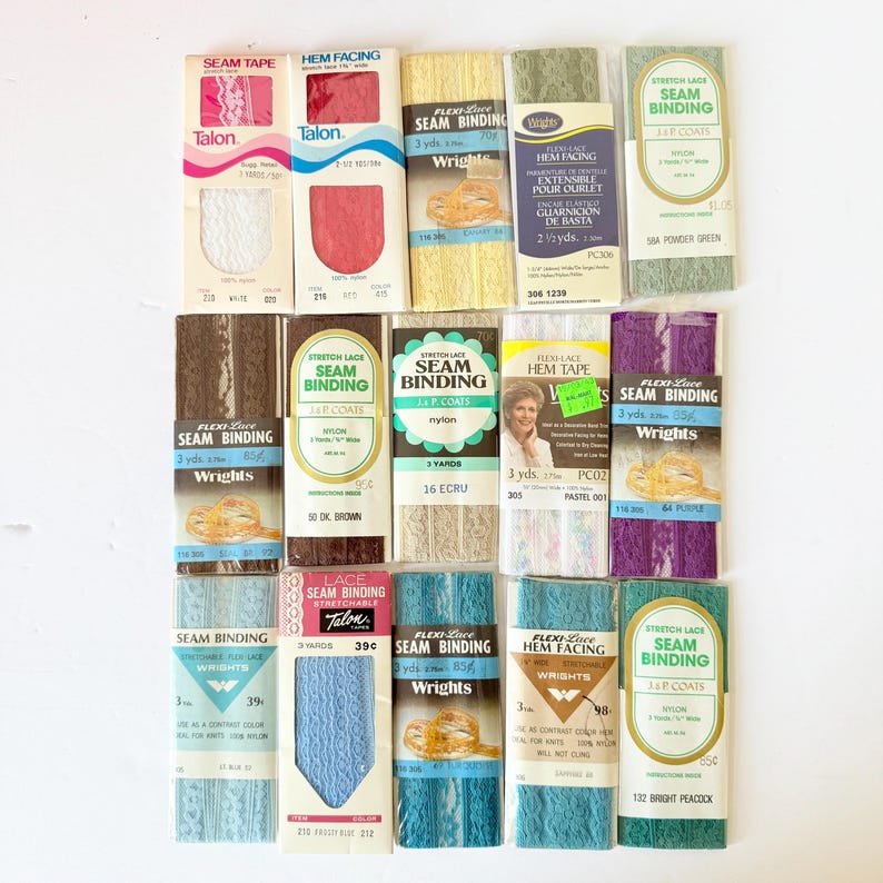 May include: A collection of vintage sewing notions, including seam tape, hem facing, and seam binding in various colors like white, pink, yellow, green, brown, and blue. The packaging features brands like Talon and Wrights.