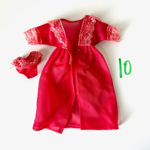 Op de afbeelding: Rode, doorschijnende badjas met kantversiering en bijpassende lingerie. De badjas heeft een V-hals en een striksluiting. De lingerie is een bh- en slipset.