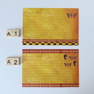 May include: Two recipe cards with a yellow and orange gradient background. The cards have lines for writing and decorative borders. One card features a butterfly, the other has butterflies and acorns. Text reads "From the Kitchen of:" and "Recipe For:"