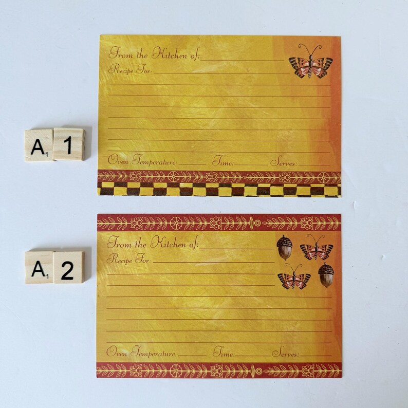 May include: Two recipe cards with a yellow and orange gradient background. The cards have lines for writing and decorative borders. One card features a butterfly, the other has butterflies and acorns. Text reads "From the Kitchen of:" and "Recipe For:"