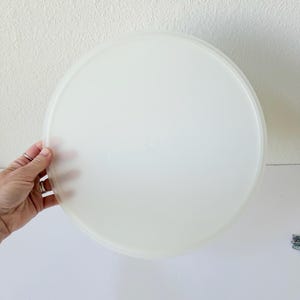 Puede incluir: Una pila de tapas de plástico blanco translúcido. Las tapas son redondas y parecen ser para recipientes de almacenamiento de alimentos. La imagen está tomada sobre un fondo blanco.