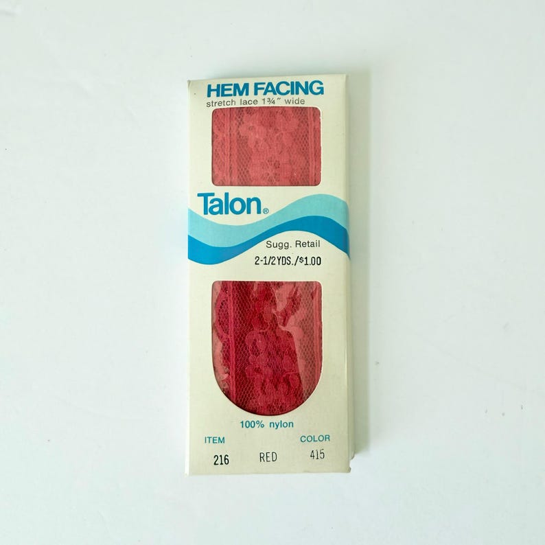 May include: A package of red stretch lace hem facing by Talon. The package has the text "HEM FACING" and "stretch lace 1 1/4" wide". The package also has the text "100% nylon", "ITEM 216", and "COLOR 415".
