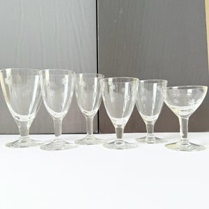 May include: A set of six clear glass stemmed drinkware. Each glass features a delicate starburst pattern etched into the glass. The collection includes various shapes, such as wine glasses and a coupe glass, suitable for serving beverages.