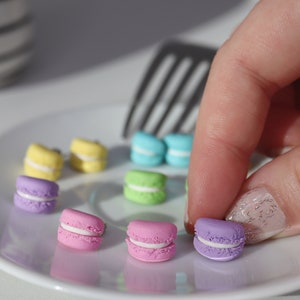 Könnte beinhalten: Ein weißer Teller mit bunten Macarons. Die Macarons sind in verschiedenen Farben, darunter rosa, grün, blau und gelb. Die Macarons sind in einem Kreis auf dem Teller angeordnet.