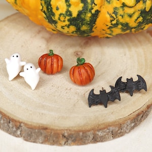 Può includere: Un set di orecchini a tema Halloween con un paio di orecchini fantasma bianchi, un paio di orecchini zucca arancioni e un paio di orecchini pipistrello neri.