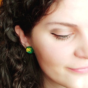 Puede incluir: Una mujer con el pelo largo y rizado casta&ntilde;o que lleva pendientes en forma de pi&ntilde;a verde y amarilla.