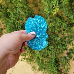 May include: A turquoise blue glitter car coaster with a cutout for a cup holder.