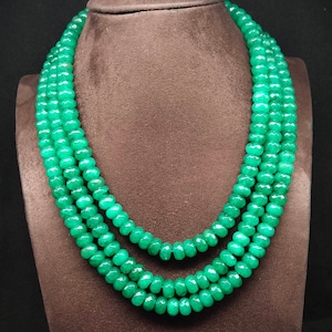 Puede incluir: Un collar de tres hileras hecho de cuentas de piedras preciosas verdes. Las cuentas son facetadas y tienen una forma ligeramente irregular.