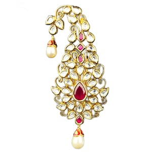 May include: A gold-toned ornate pendant with a teardrop-shaped design. The pendant is adorned with clear and pink gemstones, and features two pearl drops.