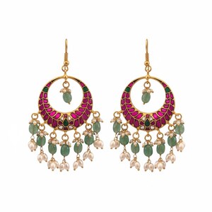 May include: A pair of gold-toned hoop earrings with a crescent-shaped design. The hoops are adorned with magenta and green accents, and feature dangling green beads and small white pearls. The earrings have a hook closure.