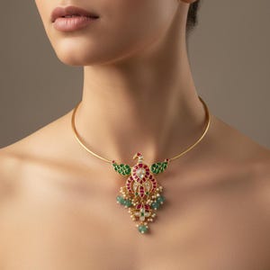 May include: A gold-toned choker necklace featuring a central peacock-shaped pendant. The pendant is adorned with red and green enamel, small white stones, and dangling light green beads with tiny white pearls, creating a detailed ornament.
