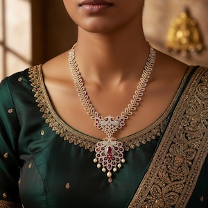 May include: A diamond necklace with a pendant featuring a large, oval ruby surrounded by smaller rubies and pearls. The necklace is worn over a dark green blouse with gold embroidery.