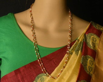 May include: A gold and red beaded necklace with white beads. The necklace is layered and has a delicate design.