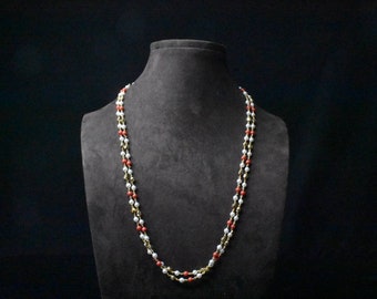 May include: A double strand necklace with white and red beads on a black velvet display stand.