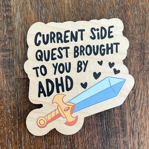 May include: Wooden sign with a blue and gold sword and the text "Current Side Quest Brought To You By ADHD" with hearts.