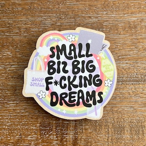 May include: A colorful sticker with a rainbow, clouds, stars, and a laptop. The sticker says "Small Biz Big F*cking Dreams" with the words "Shop Small" in a smaller font.