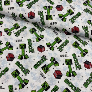 May include: White fabric with a repeating pattern of green pixelated creatures, red TNT blocks, and the word "BOOM!" in green. The design also includes the text "SSS..." in black. The fabric has a light blue cloud-like background.