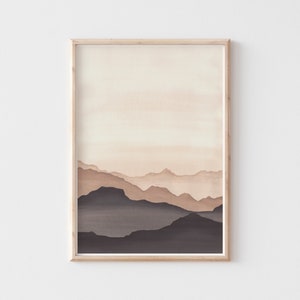 May include: A framed watercolor print featuring a layered mountain landscape in shades of brown and beige. The artwork has a minimalist style, with soft gradients creating depth and a sense of calm. The frame is a light wood color.
