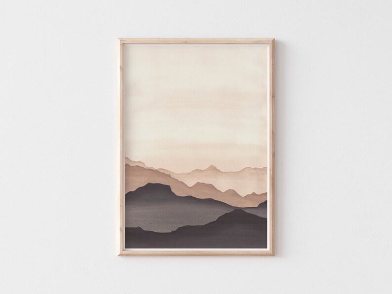 May include: A framed watercolor print featuring a layered mountain landscape in shades of brown and beige. The artwork has a minimalist style, with soft gradients creating depth and a sense of calm. The frame is a light wood color.