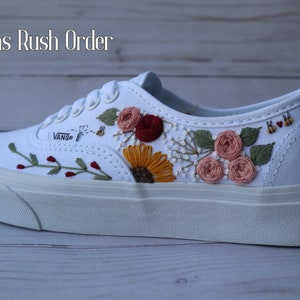 Könnte beinhalten: Weiße Vans-Sneaker aus Canvas mit gestickten Blumen und dem Datum "5.21.22" an der Seite.