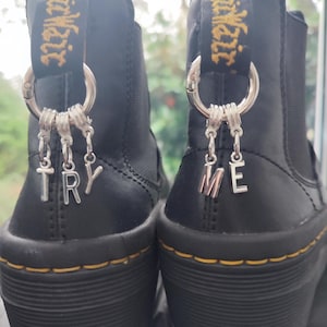 May include: Black leather ankle boots with silver charms that spell out "TRY ME".