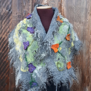 Puede incluir: Una bufanda de lana gris con textura peluda y bordado floral de colores. La bufanda presenta detalles en naranja, amarillo, verde y morado.