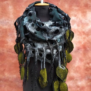 May include: A black, green, and white felted scarf with green leaf accents. The scarf has a unique, open-weave design and is displayed on a black mannequin.