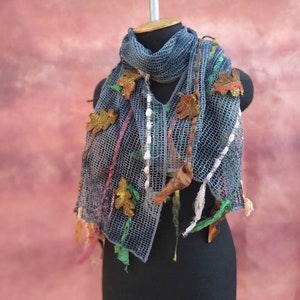 Peut inclure: Une écharpe en crochet bleu avec des accents colorés et des embellissements en forme de feuilles d'automne.