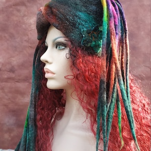 May include: A dark green and brown felted hat with long, colorful wool dreadlocks. The hat has a small embroidered flower design.