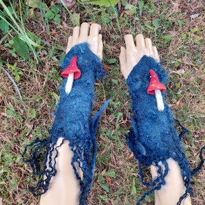 May include: A pair of blue fingerless gloves with a mushroom design. The mushrooms are red with white stems and are attached to the gloves with a white thread.