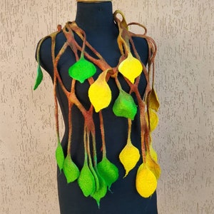 May include: A brown, green, and yellow felted necklace with a leafy design. The necklace is displayed on a black mannequin.
