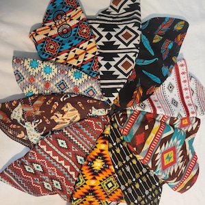 May include: A collection of bandanas with various Southwestern and Native American-inspired patterns. The bandanas feature geometric designs, arrows, feathers, and wagon wheel motifs in a variety of colors including red, blue, brown, and black.