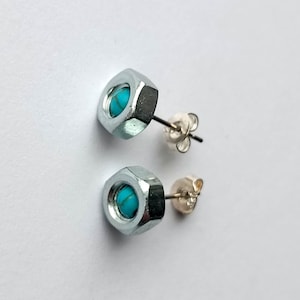 May include: A pair of silver stud earrings with turquoise stones set in the centre of a hexagonal nut.