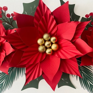 May include: Three large red paper poinsettia flowers with gold glitter ornaments in the center. The flowers are surrounded by green paper leaves.