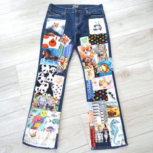 Op de afbeelding: Donkerblauwe spijkerbroek van denim met een patchworkontwerp op de voorpijpen. De patches bestaan uit diverse kleurrijke stoffen vierkanten met illustraties van dieren, waaronder panda's, vossen, honden, paarden, uilen, vissen en een zeepaardje.