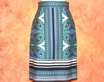 May include: A knee-length pencil skirt featuring a vibrant geometric and paisley pattern in shades of blue, teal, white, and black. The skirt has a high waistband and a horizontal striped border at the hem, creating a structured and symmetrical look.